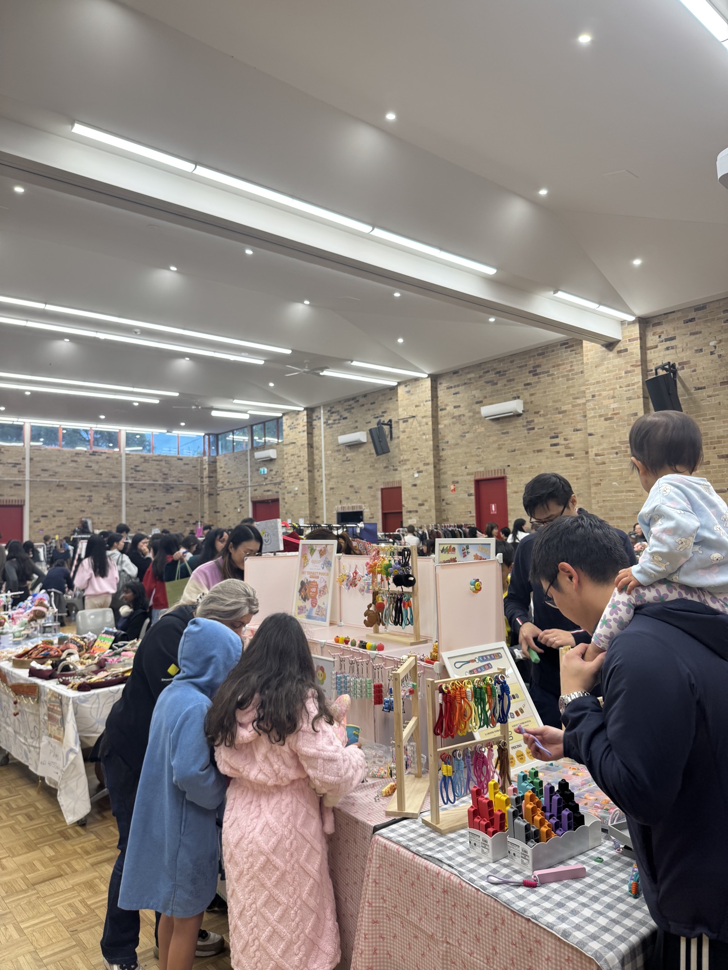 A family browsing a table of colourful handmade keychains and trinkets