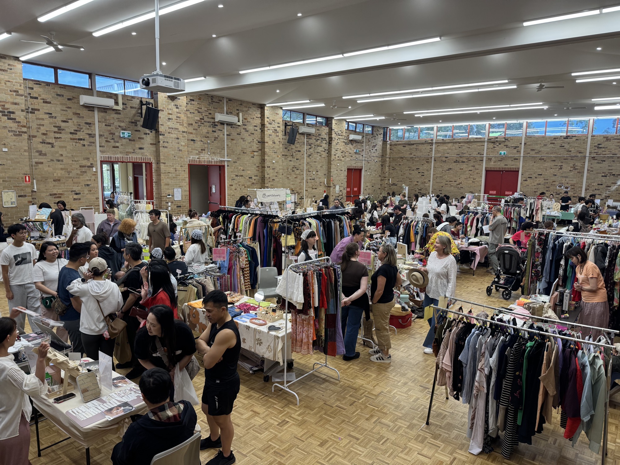 A packed view of the Cherrybrook hall, with clothing racks, stall tables and crowds of shoppers